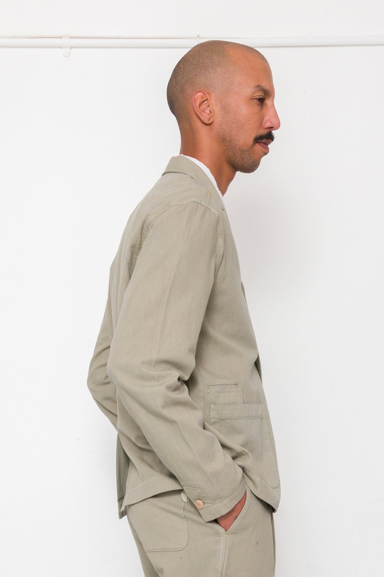 Man wearing a beige suit standing against a white background