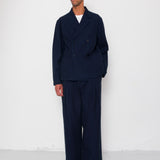 Man wearing a navy blue suit standing against a white background