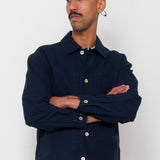 Man wearing a navy jacket and blue cap against a white background