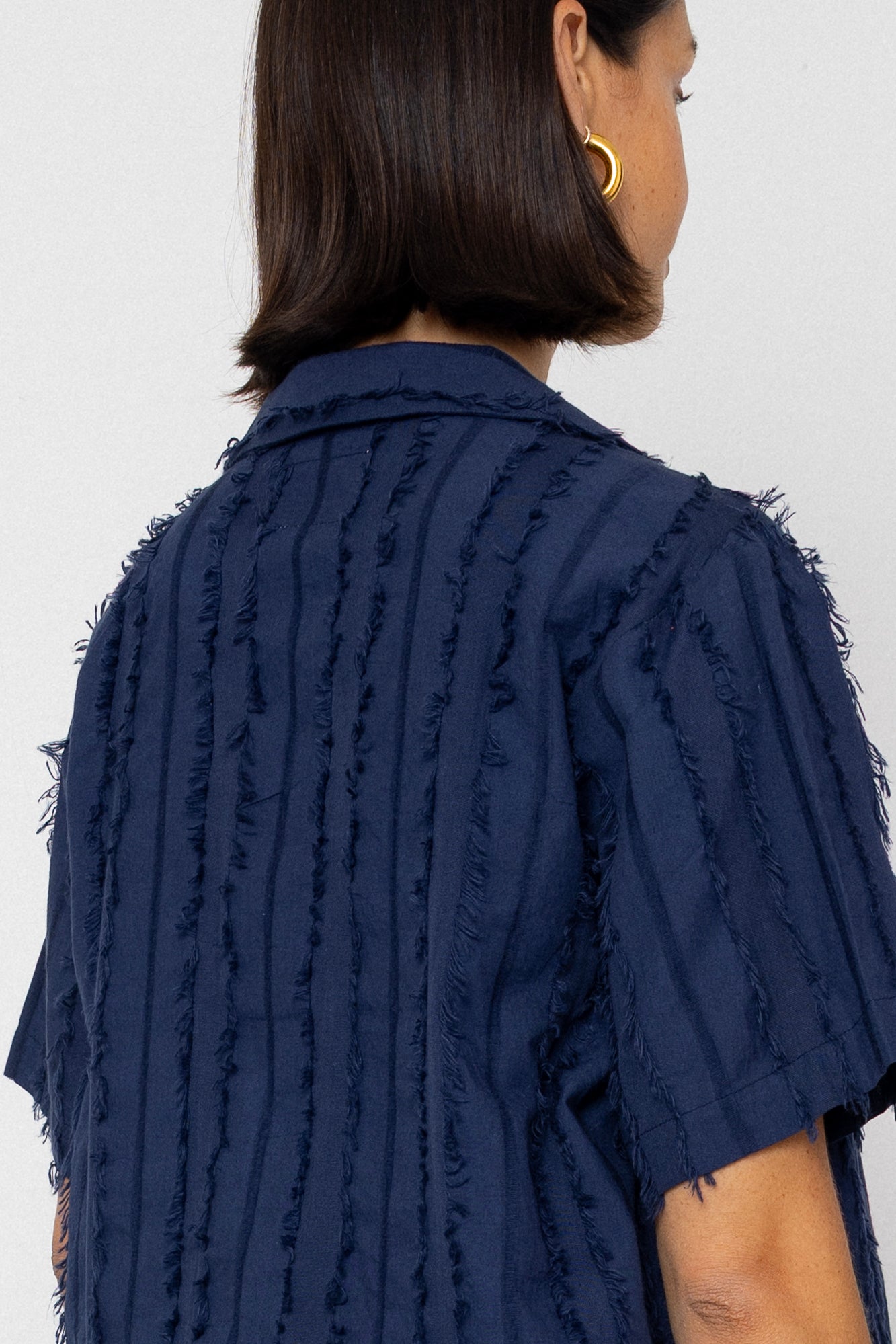 Navy blue textured shirt worn by a person on a white background