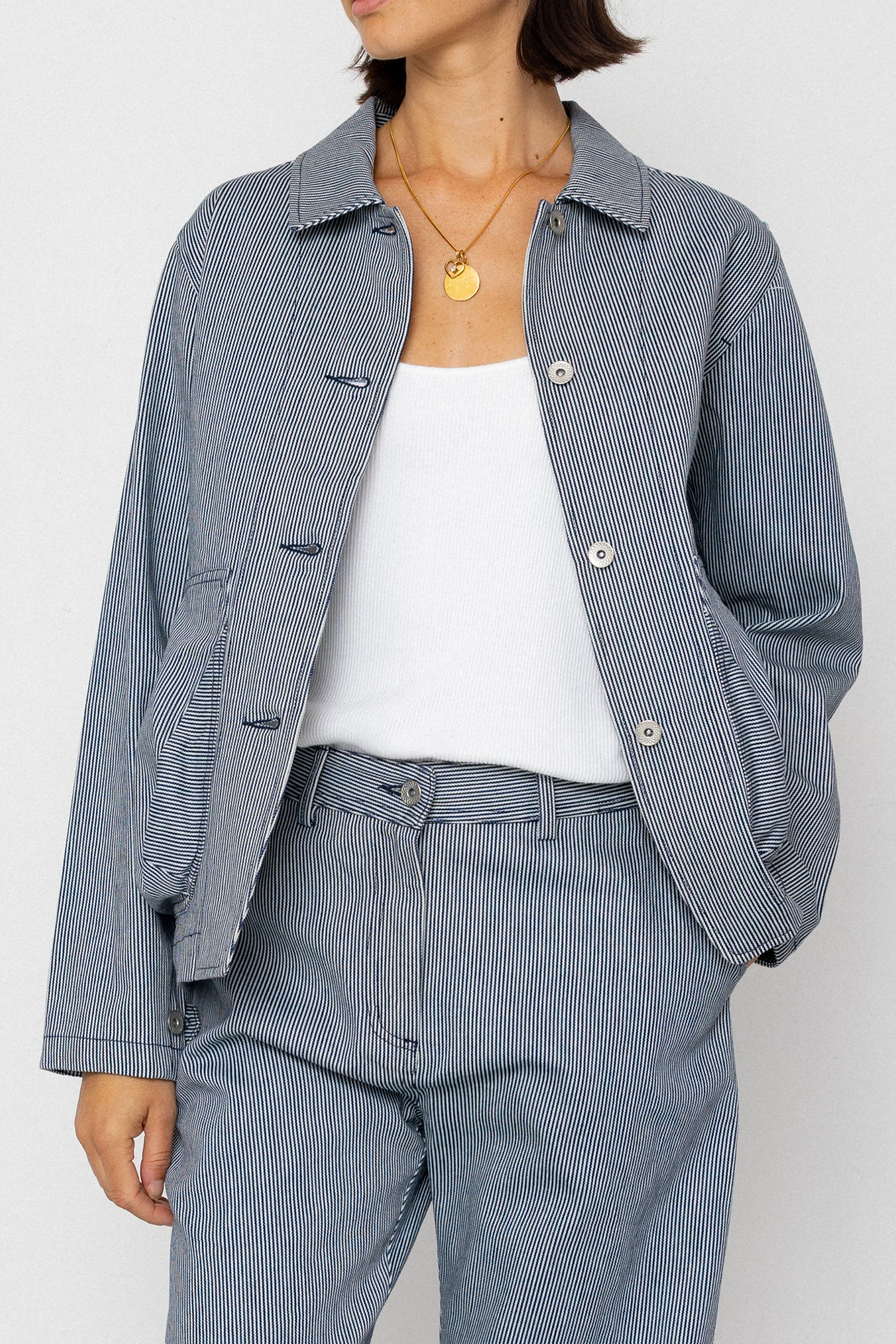 Person wearing a blue and white striped outfit with a white shirt underneath on a white background