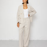 Person wearing a beige suit with a white top on a white background
