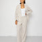 Person wearing a beige suit with a white top on a white background
