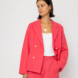 Woman wearing a coral suit with a white top against a white background