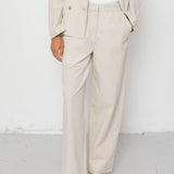 Person wearing a beige suit with white shirt and sandals on a white background