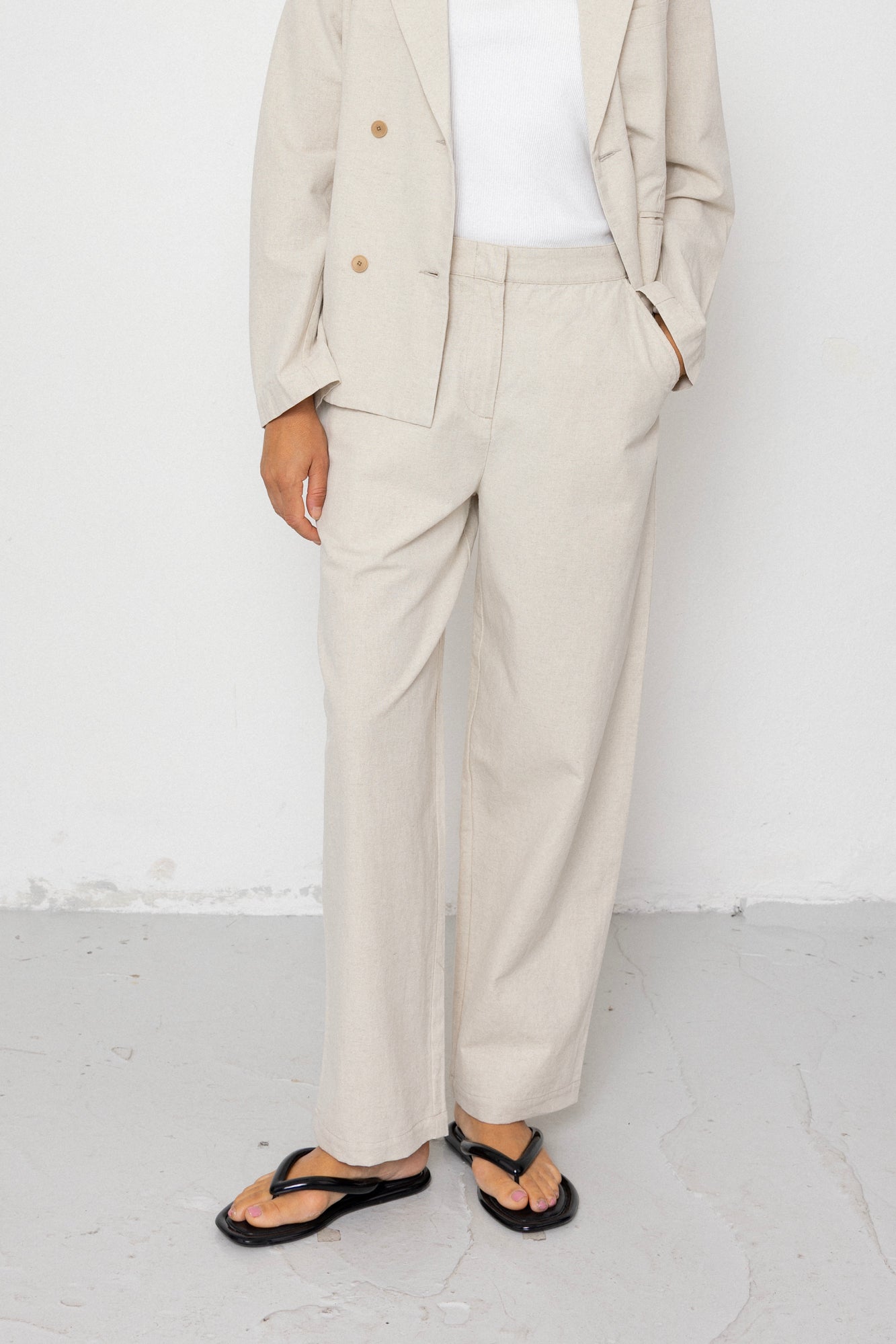 Person wearing a beige suit with white shirt and sandals on a white background
