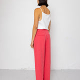 Person wearing a white top and pink pants standing against a white background