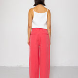 Person wearing a white tank top and coral pants on a white background