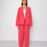 Person wearing a coral pink suit against a white background