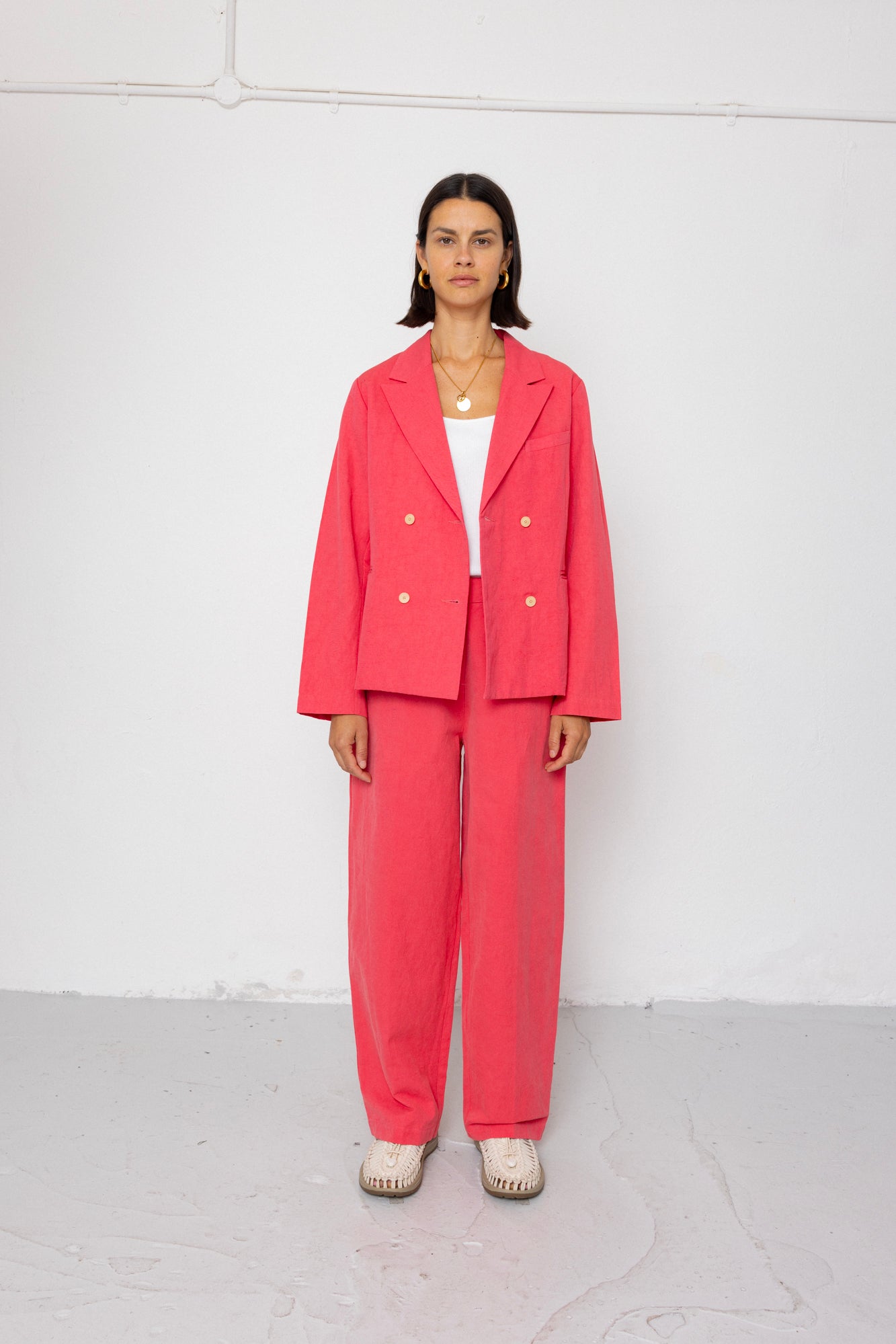 Person wearing a coral pink suit against a white background