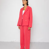 Woman wearing a pink suit standing against a white background