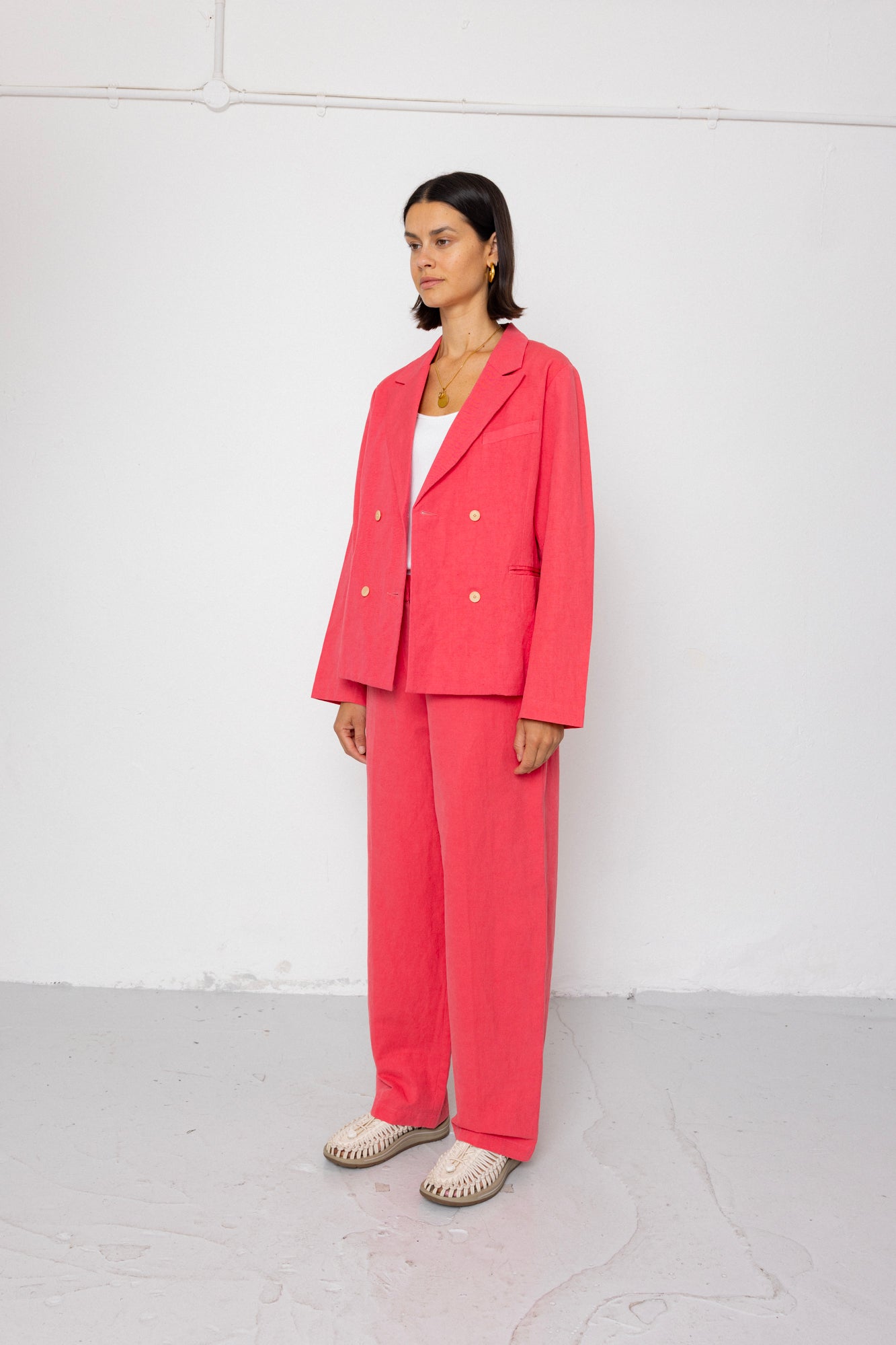 Woman wearing a pink suit standing against a white background