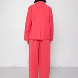 Person wearing a coral suit standing against a white background