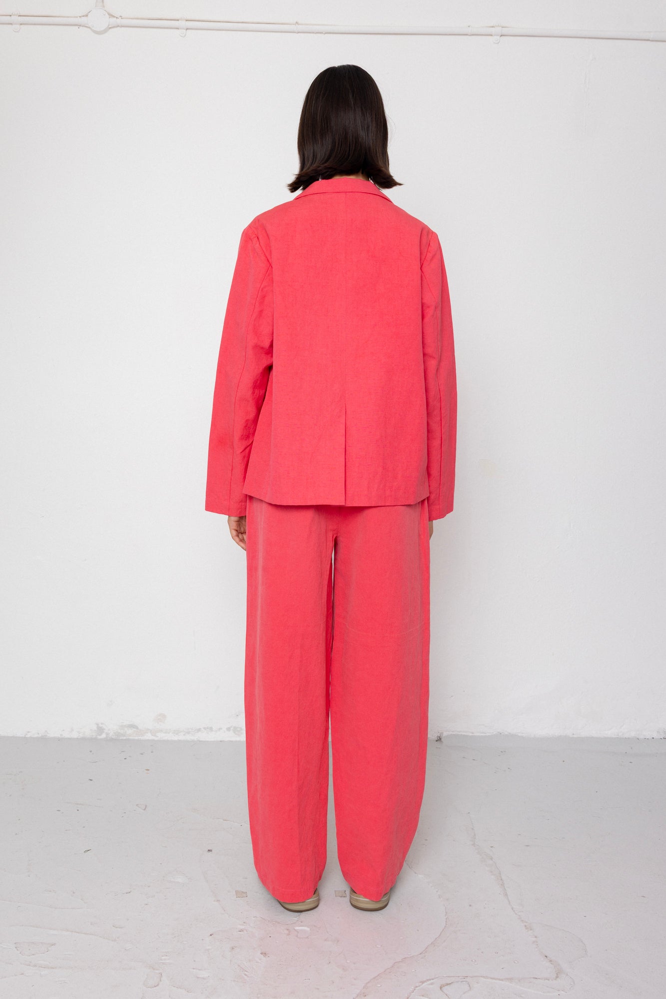 Person wearing a coral suit standing against a white background
