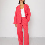 Woman wearing a coral suit against a white background