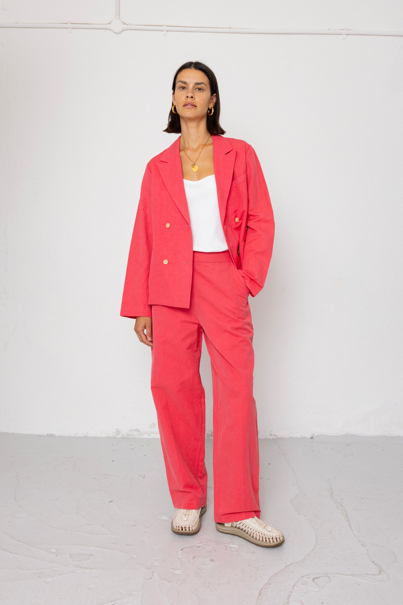 Woman wearing a coral suit against a white background