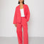 Woman wearing a coral suit against a white background