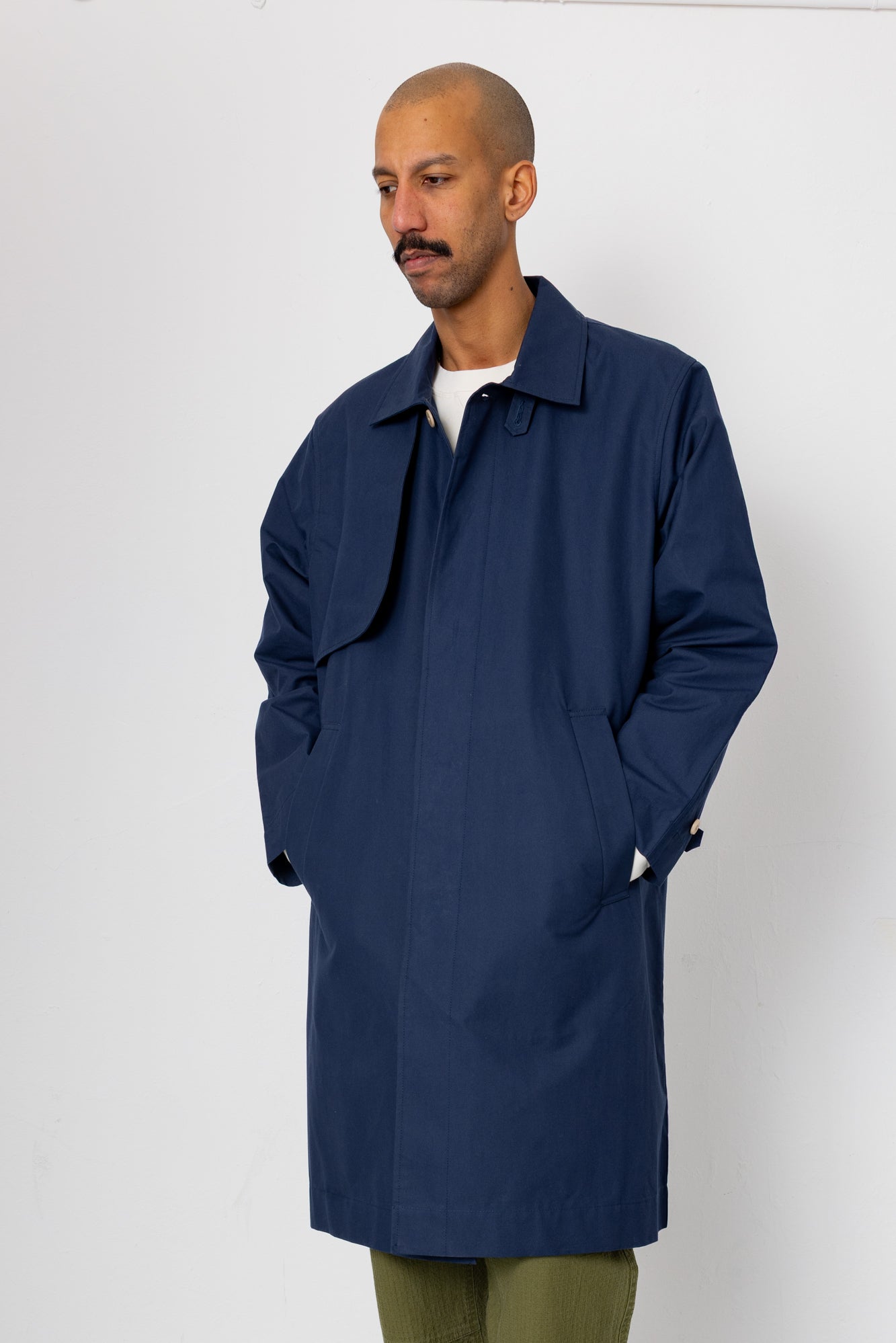 Man wearing a navy blue coat against a white background