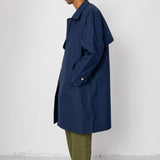 Man wearing a navy trench coat over a green outfit against a white background