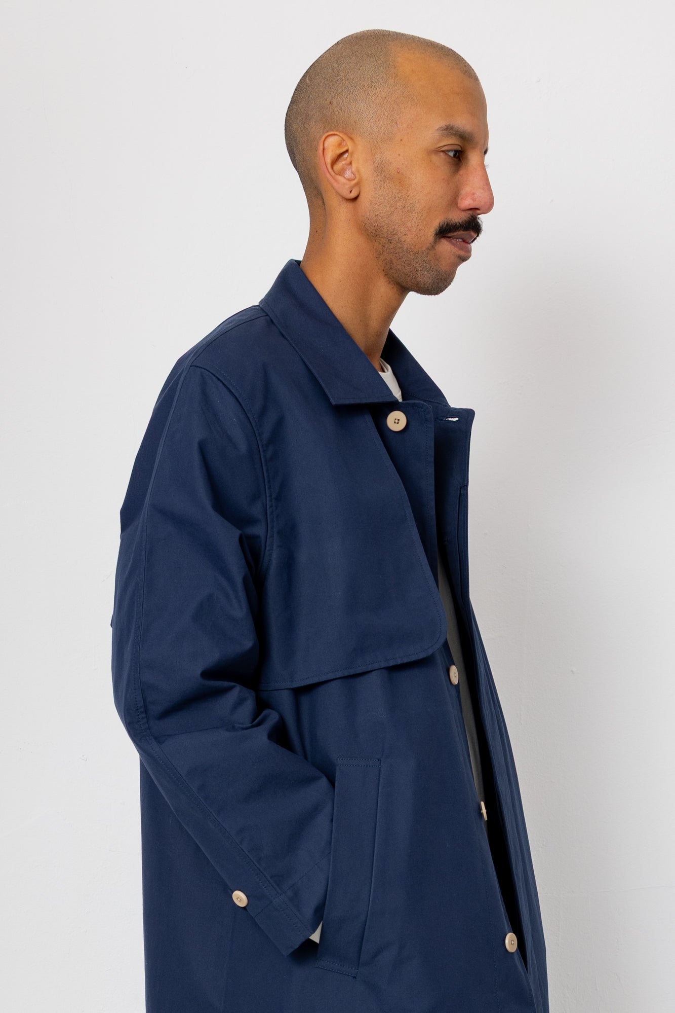 Man wearing a navy blue jacket with button details on a white background