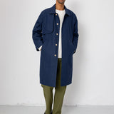 Man wearing a navy coat, white shirt, green pants, and black shoes against a white background