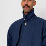 Man wearing a dark blue coat with a high collar on a white background