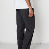 Person wearing black pants and gray sneakers against a white background