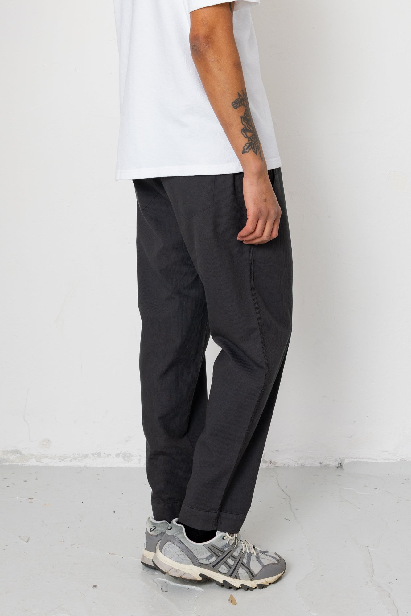 Person wearing black pants and gray sneakers against a white background
