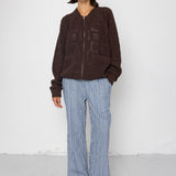 Person wearing a brown jacket and blue striped pants against a white background