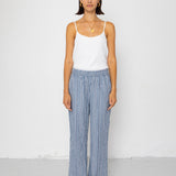 Woman wearing a white tank top and blue striped pants on a white background