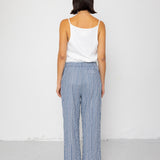 Person wearing a white tank top and blue striped pants against a white background