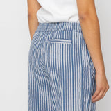 Person wearing blue and white striped pants with a plain background
