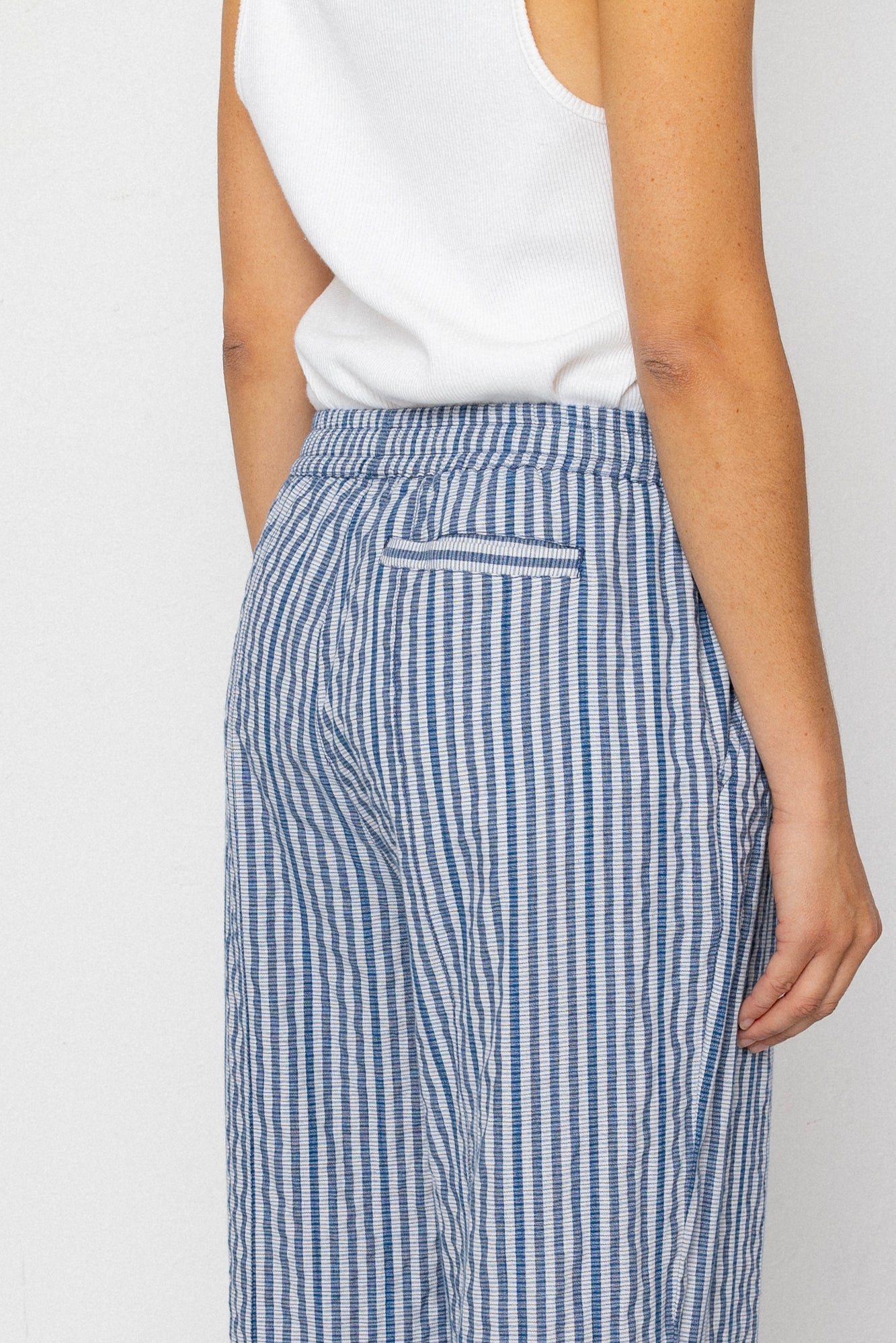 Person wearing blue and white striped pants with a plain background