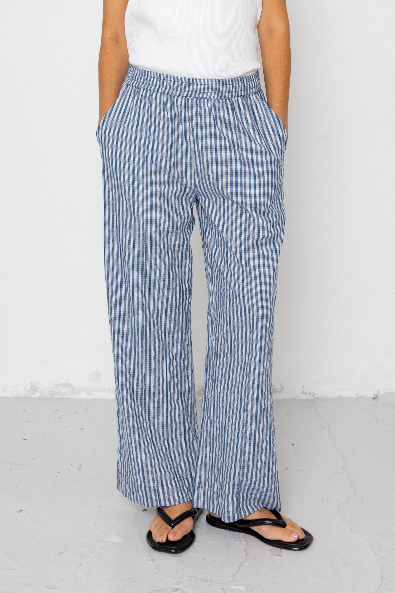 Person wearing blue and white striped pants on a white background