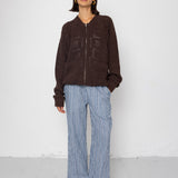 Person wearing a brown jacket and blue striped pants against a white background