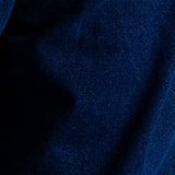 A close-up of dark blue textured fabric with a fine woven pattern and soft folds.