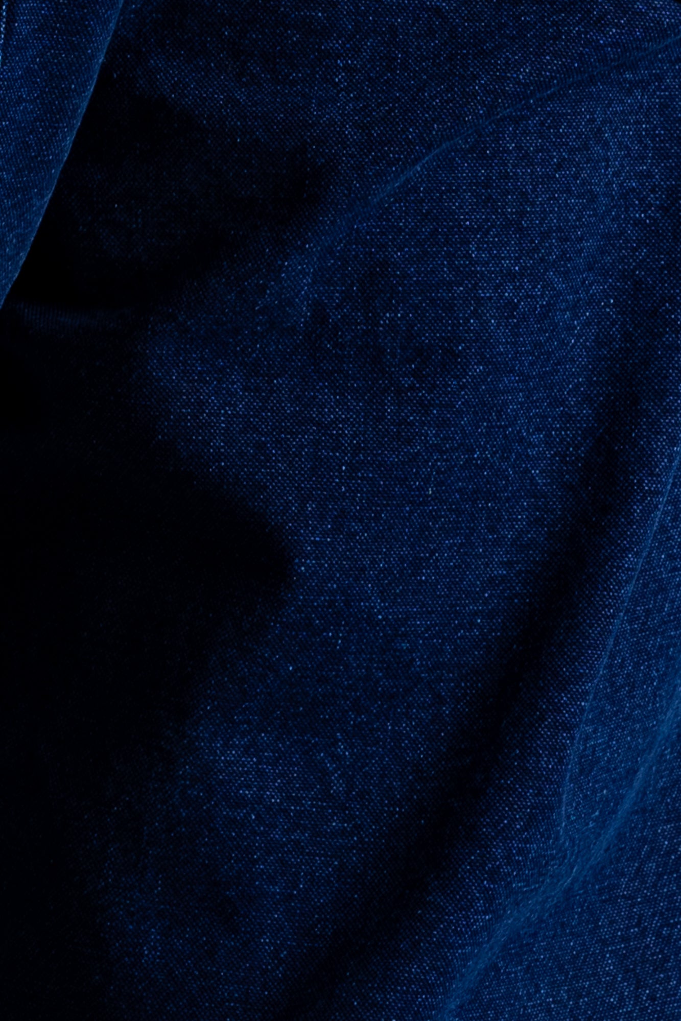 A close-up of dark blue textured fabric with a fine woven pattern and soft folds.