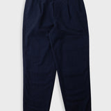 A pair of dark navy blue trousers with front pleats, laid flat against a light gray background.