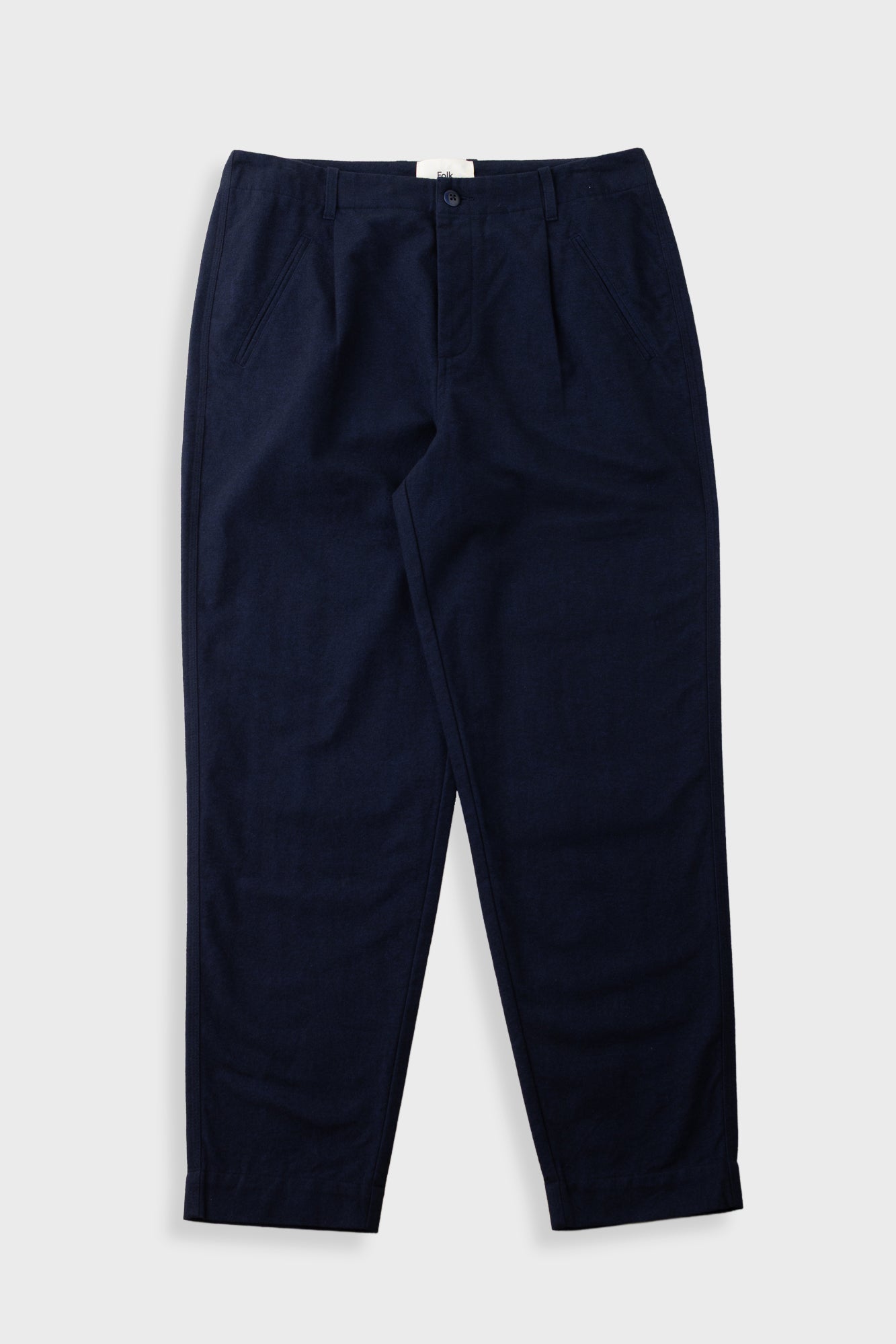 A pair of dark navy blue trousers with front pleats, laid flat against a light gray background.