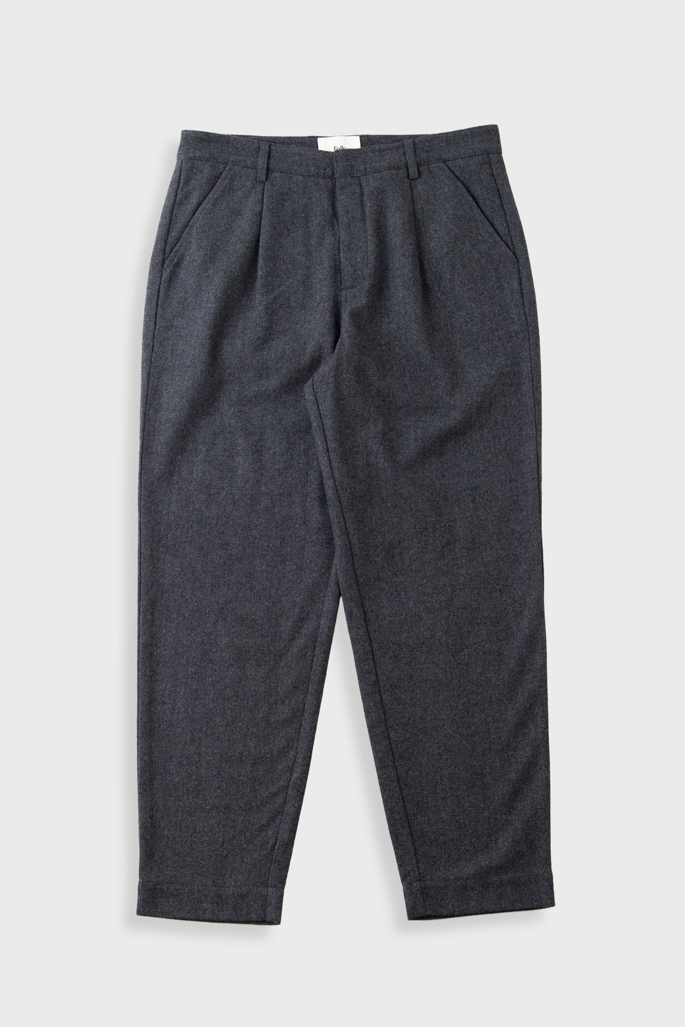 Grey trousers laid flat against a light grey background