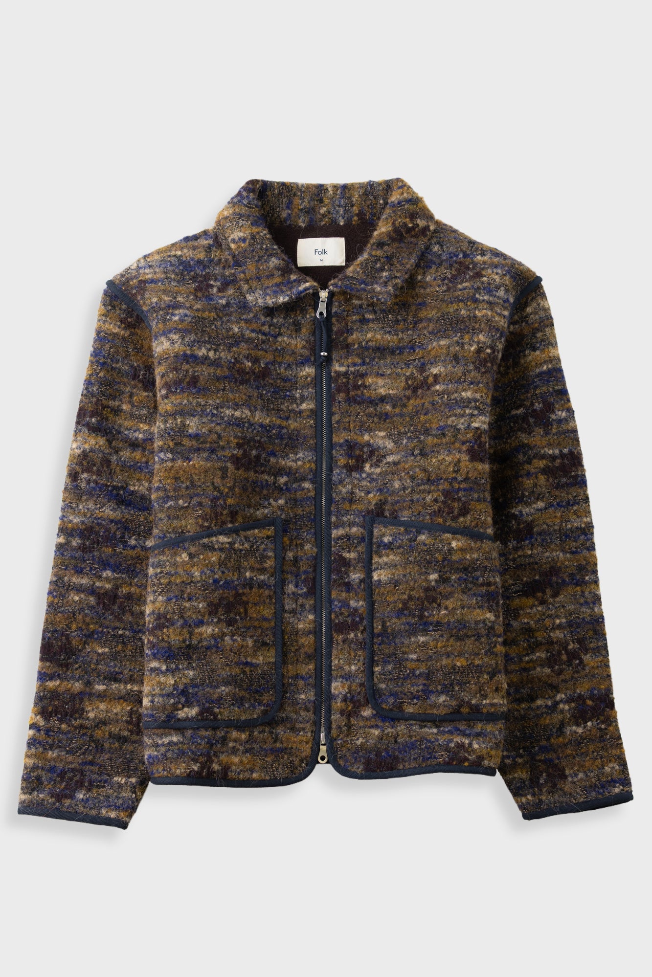 A zip-up jacket featuring a textured, marled tweed pattern in navy blue, brown, and gold. It has a stand-up collar, a front zipper, and two large front patch pockets with dark piping, shown against a light gray background.
