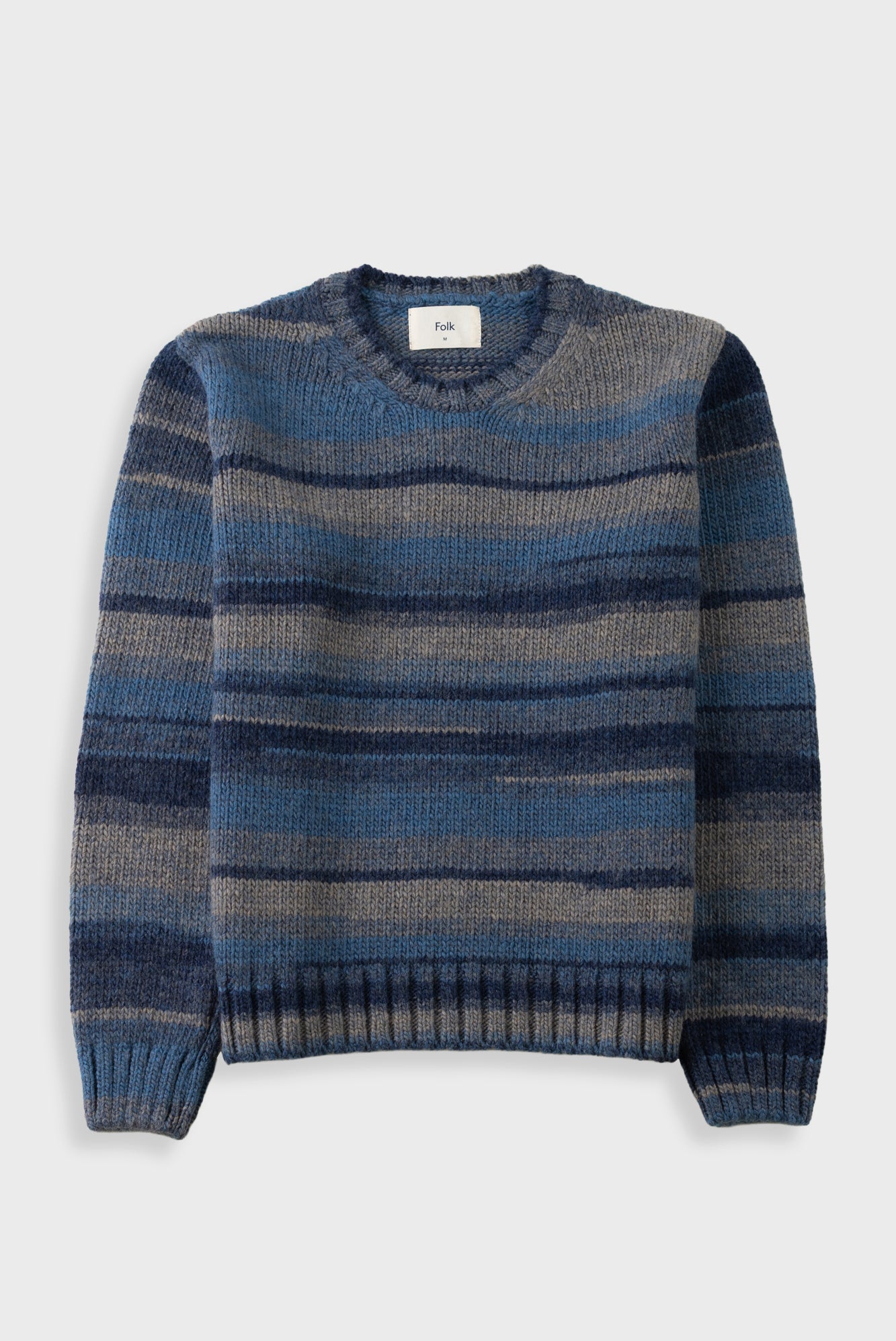 A crewneck knit sweater with horizontal stripes in shades of blue, navy, and gray, displayed flat against a light gray background.