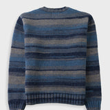 A striped knit sweater with horizontal bands of navy, medium blue, and gray, shown from the back against a light gray background.