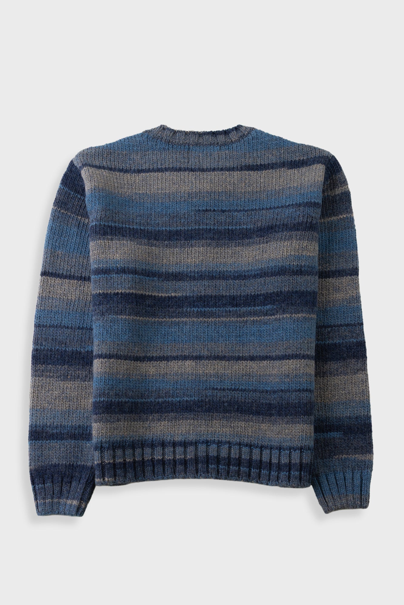 A striped knit sweater with horizontal bands of navy, medium blue, and gray, shown from the back against a light gray background.