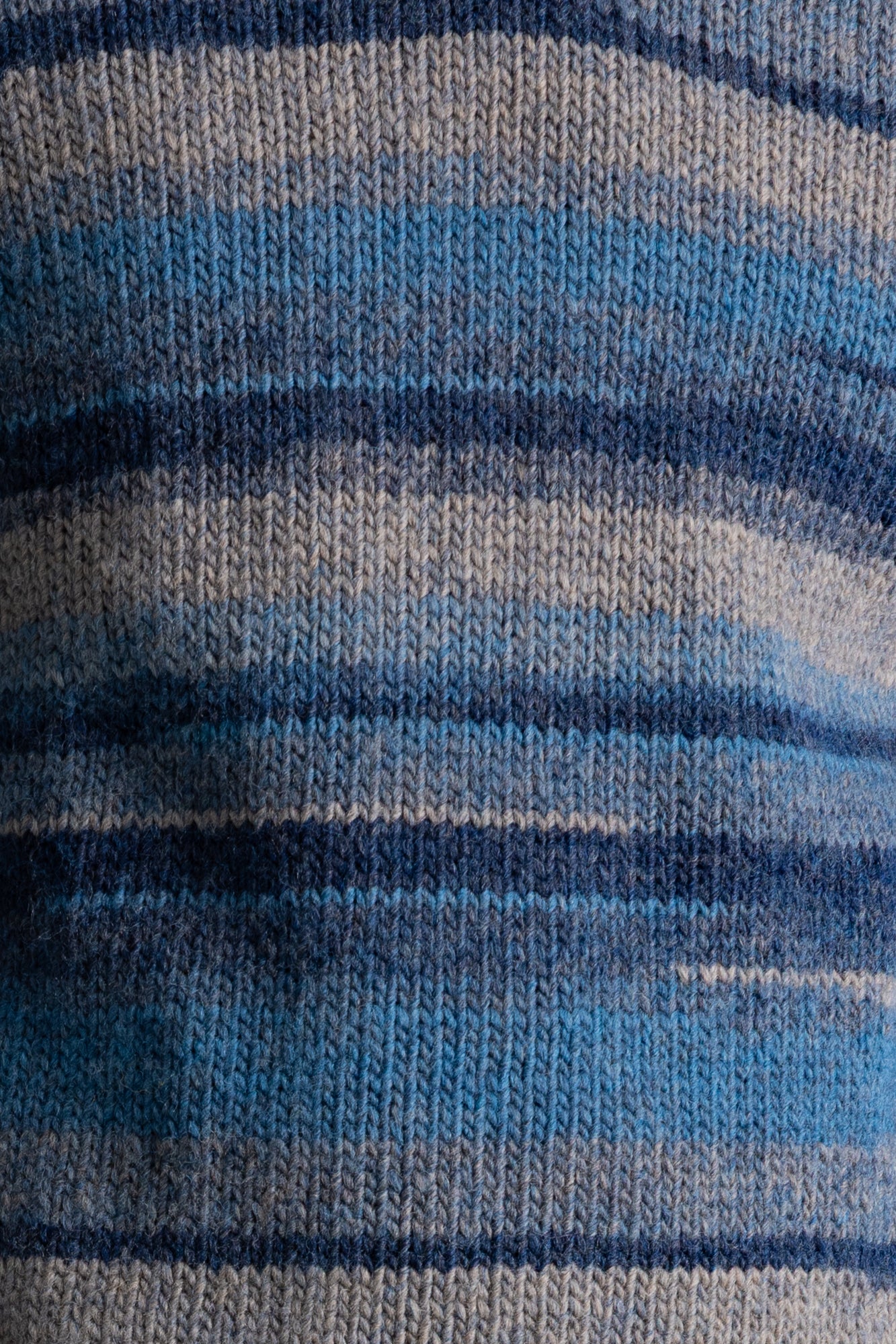 Close-up of a knitted fabric with horizontal stripes in shades of blue, navy, and gray.