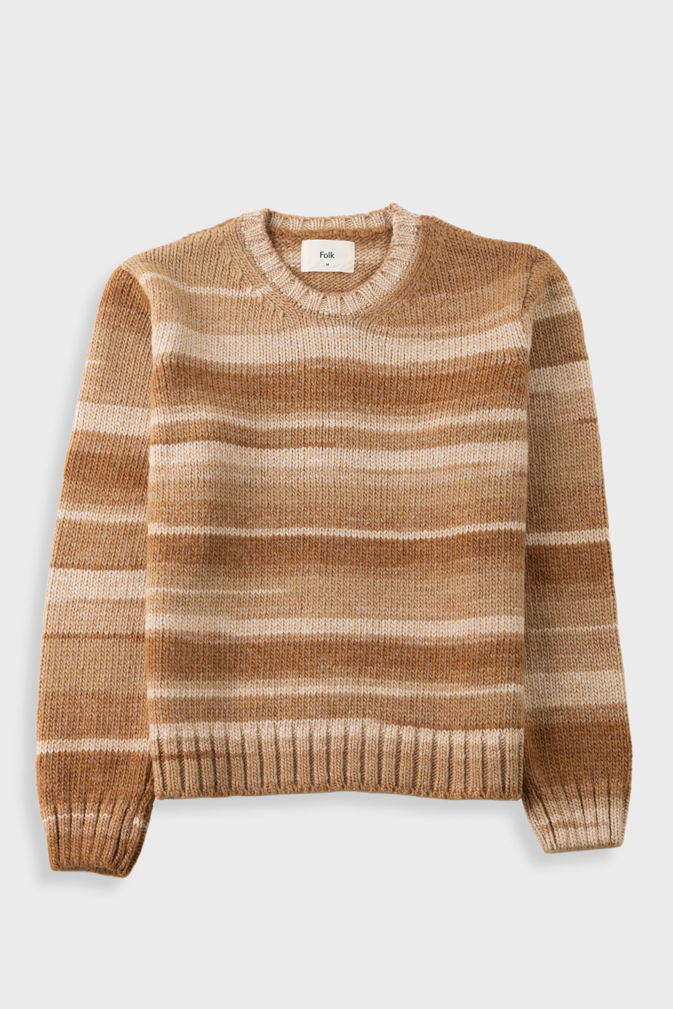 A long-sleeve crewneck knit sweater with horizontal stripes in shades of tan, brown, and cream, displayed flat against a light gray background.