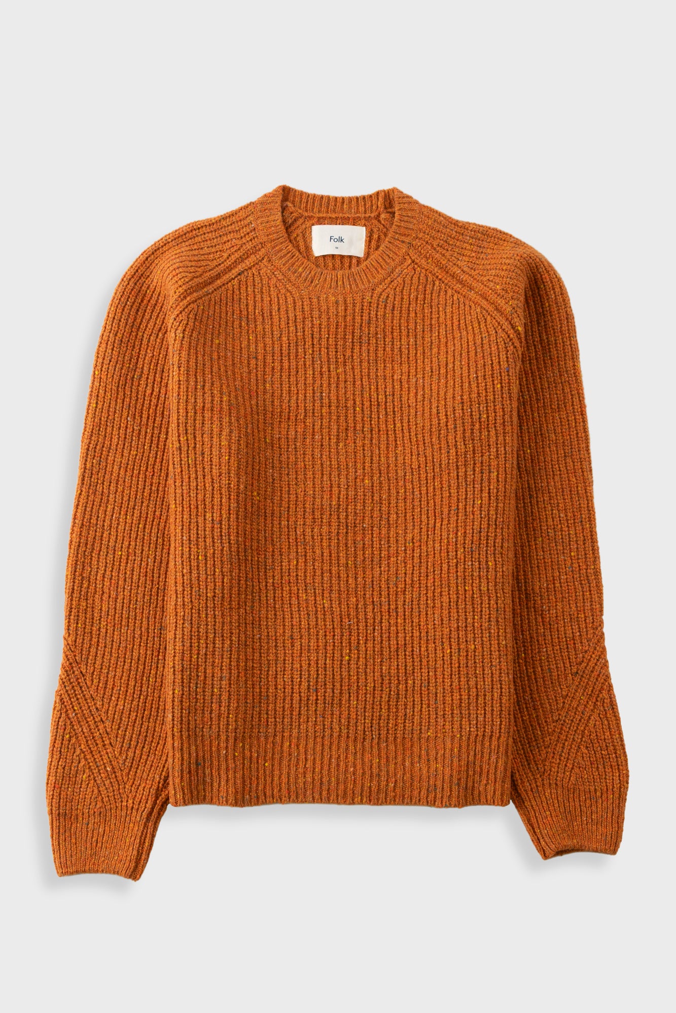 Orange knitted jumper against a light grey background