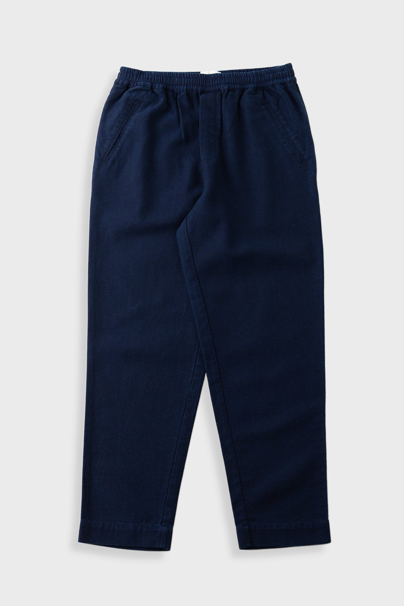 Navy trousers with an elasticated waistband, laid flat against a light grey background