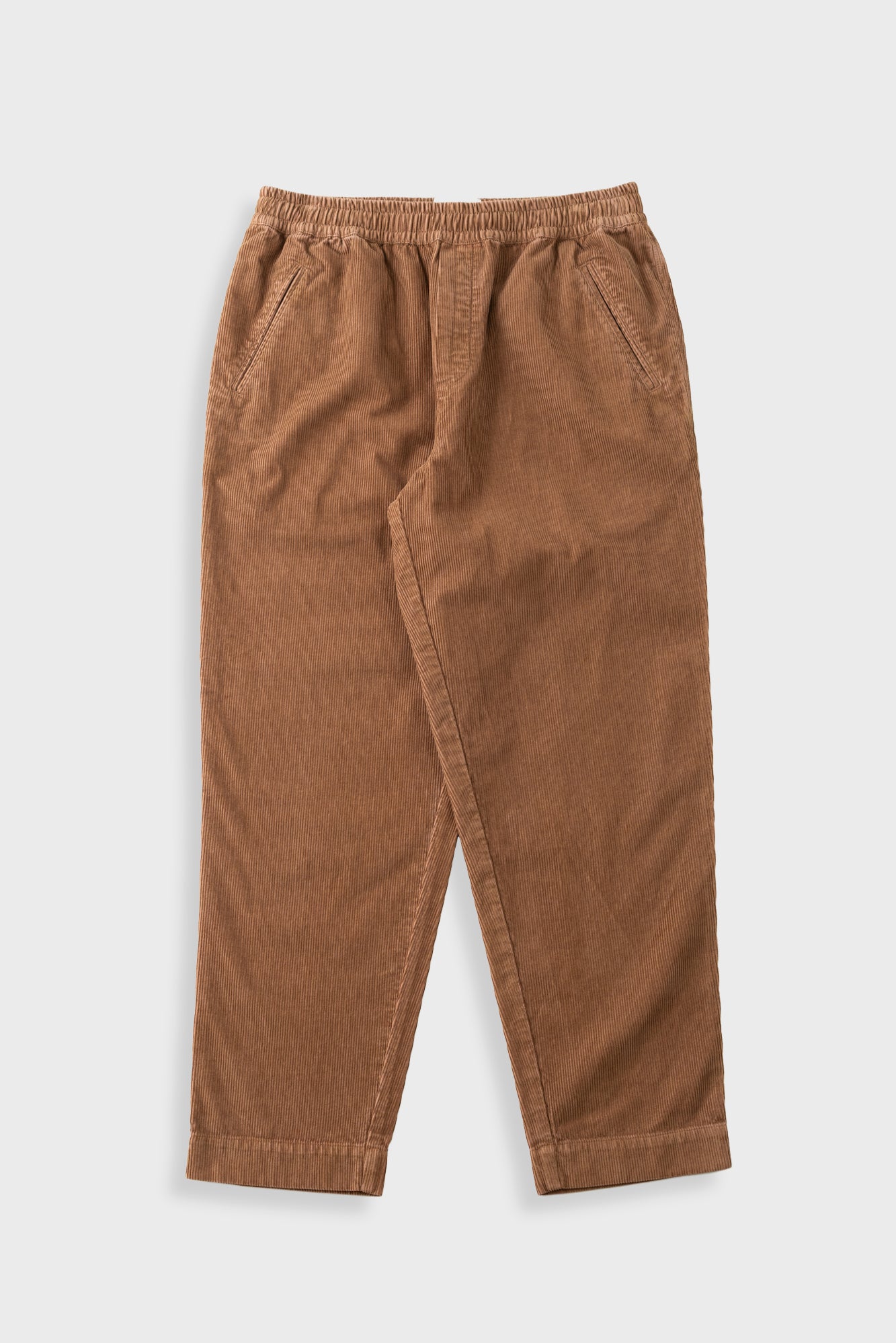 Orange brown cord trousers with elasticated waistband against a light grey background