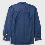 A blue denim long-sleeve button-up shirt shown from the back, featuring a collar, chest pocket, and buttoned cuffs, photographed on a light gray background.